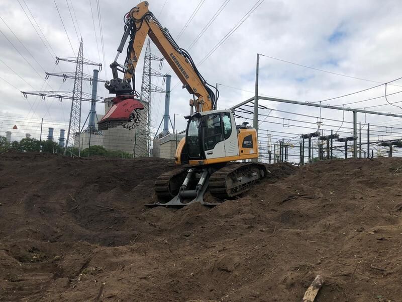 Ein großer gelber Bagger arbeitet auf einem Feld.