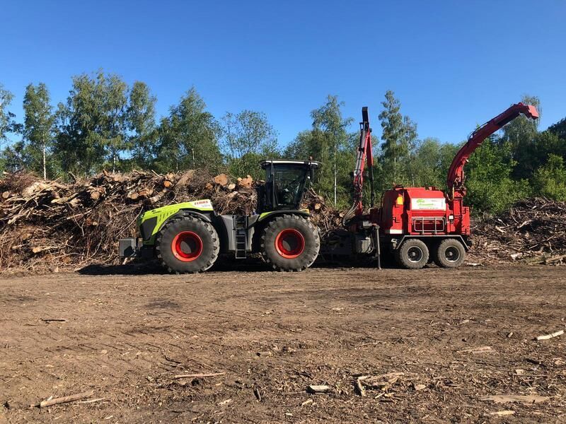 Ein Traktor und ein Häcksler stehen nebeneinander auf einem Feld.