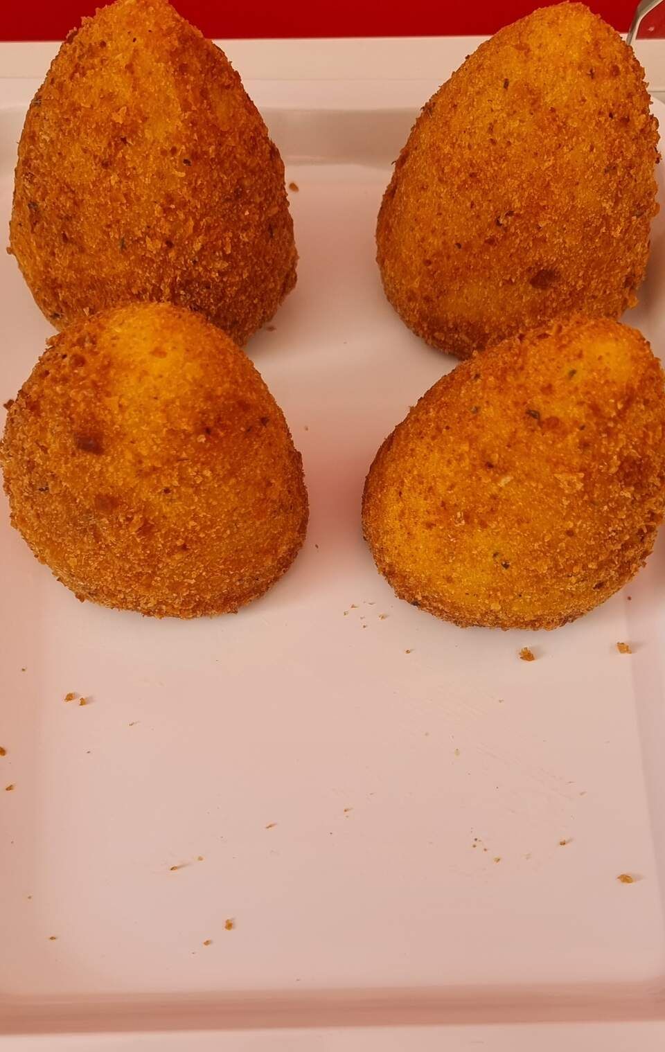 Quatre boules de nourriture frite sont sur une assiette blanche.