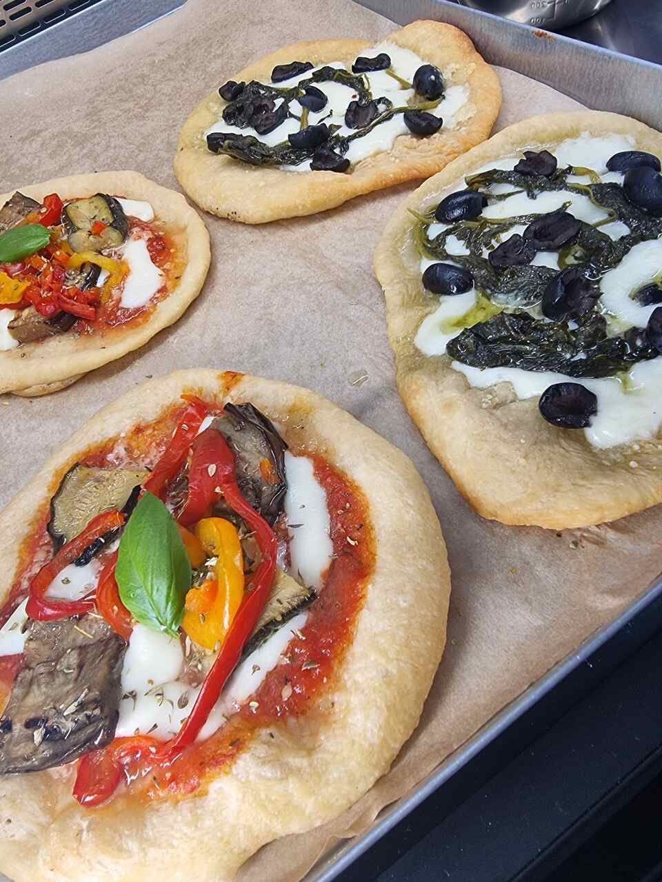 Quatre pizzas avec des garnitures différentes sont sur un plateau