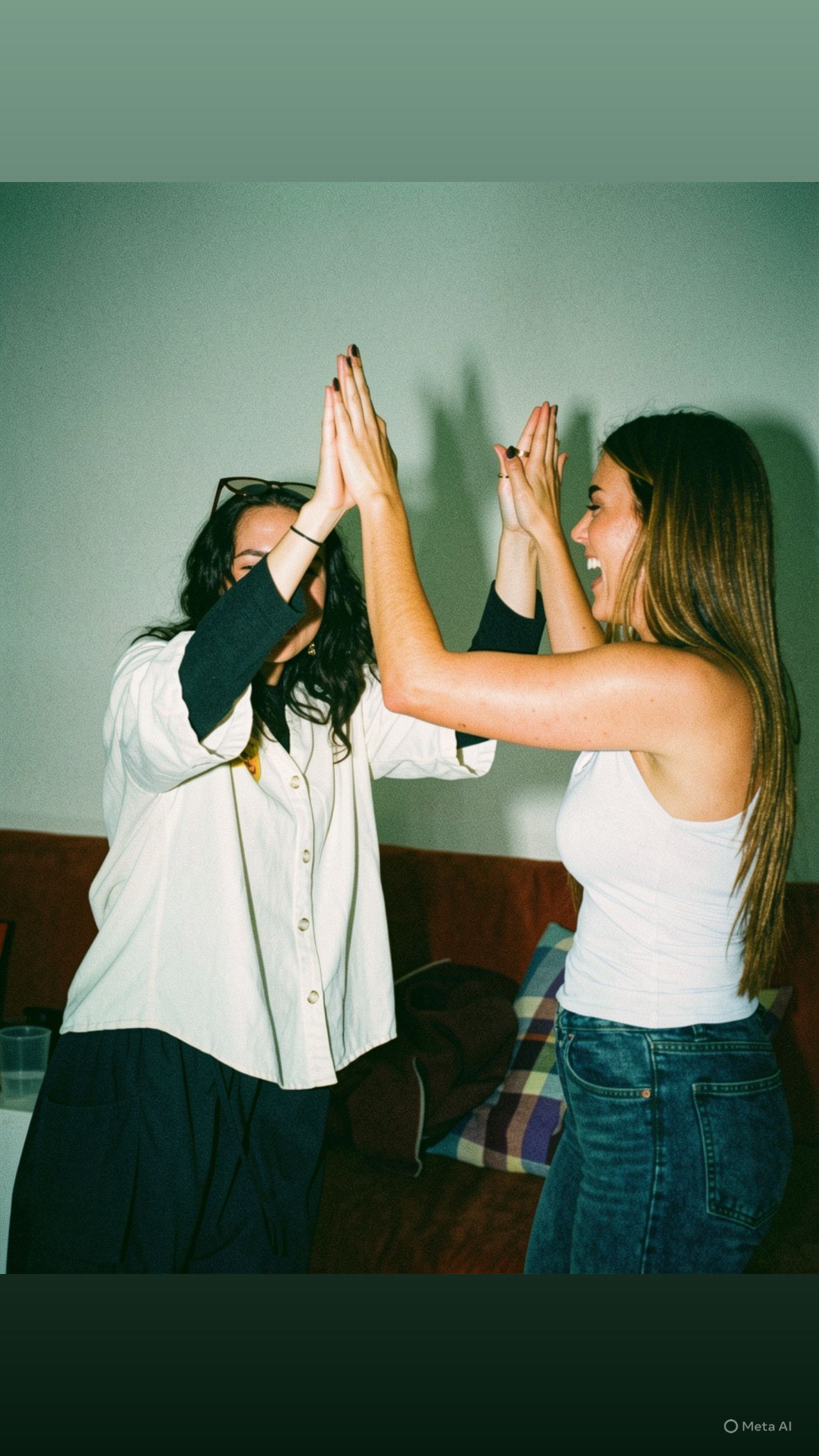 Dos personas conversando en una habitación luminosa, con estanterías y una lámpara colgante al fondo.