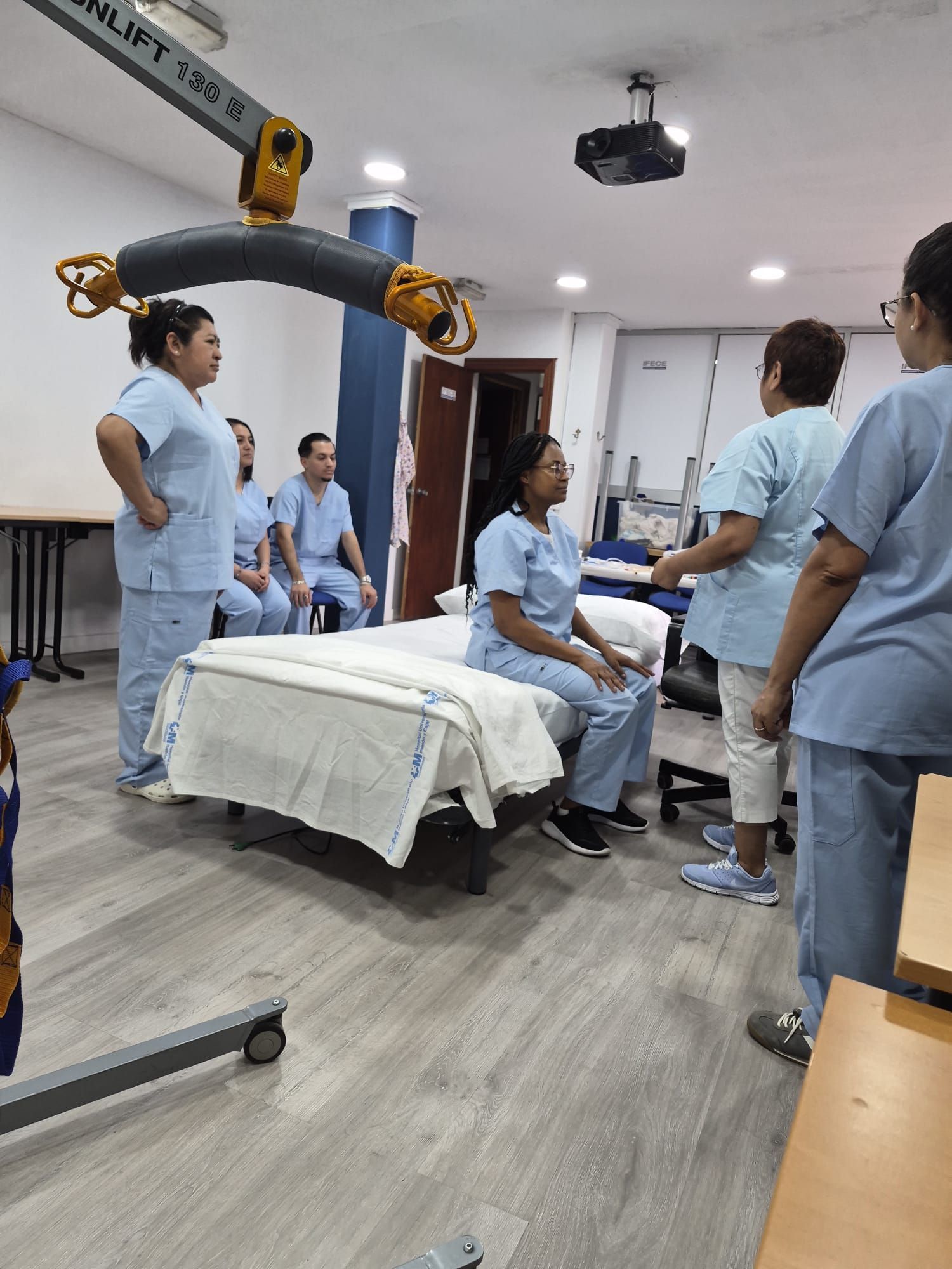 Trabajador sanitario con uniforme azul de pie en el pasillo de un hospital.
