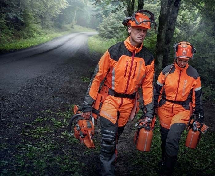 Un hombre y una mujer caminan por una calle llevando motosierras.