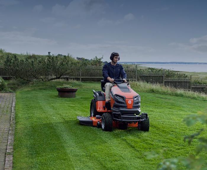Un hombre conduce una cortadora de césped sobre un césped verde y exuberante.