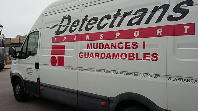 Furgoneta de transporte Detectrans de color blanco con letras rojas y negras, estacionada en una calle.