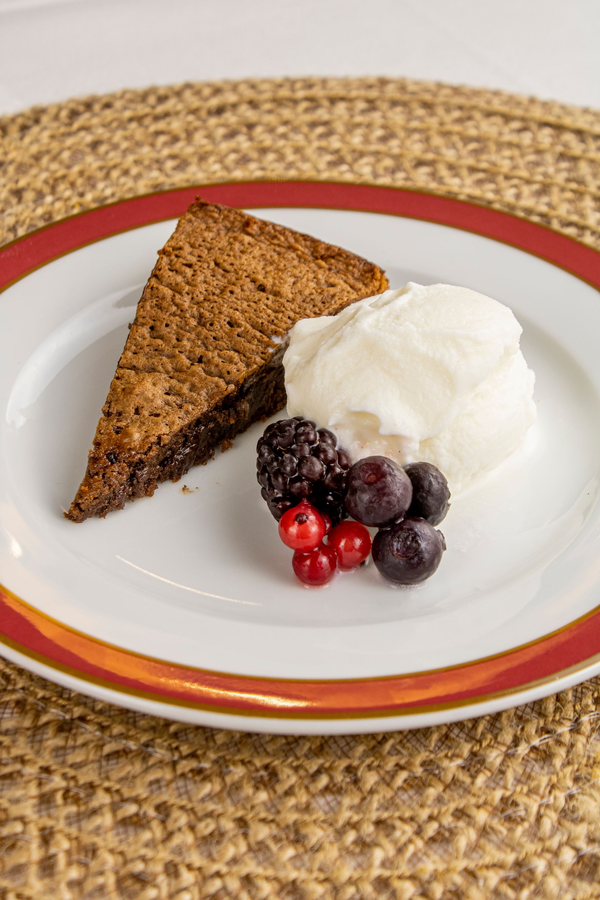 Fatia de brownie com sorvete e frutas vermelhas em um prato.