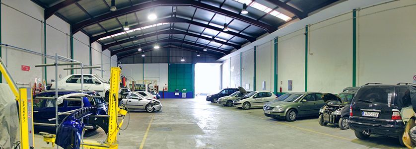 Un gran almacén lleno de coches y camiones.