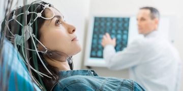 Una mujer está acostada en una cama de hospital haciéndose una prueba de EEG.