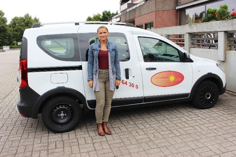 Frau steht neben einem weißen Lieferwagen mit einem Logo an der Seite.