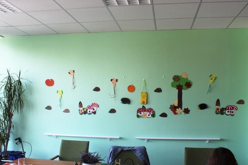 Eine Wand, die mit bunten Papierausschnitten einer Herbstszene, darunter Bäume, Häuser und Drachen, dekoriert ist.