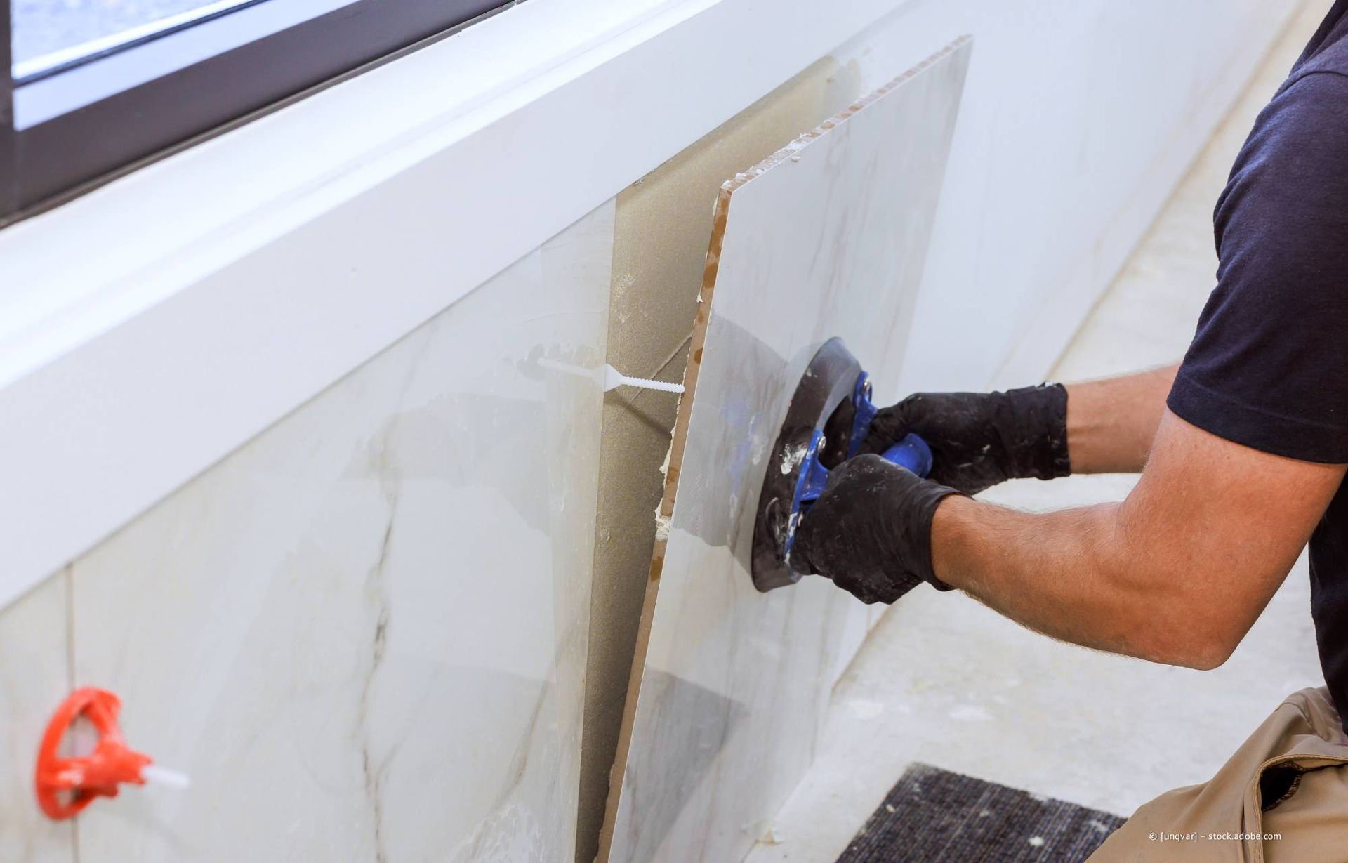 Eine Frau vergleicht Farbmuster mit Fliesenproben in einem Ausstellungsraum.