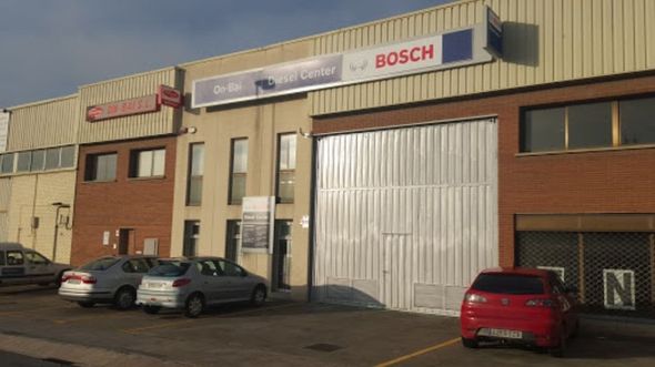 Un coche rojo está aparcado delante de un edificio de Bosch.