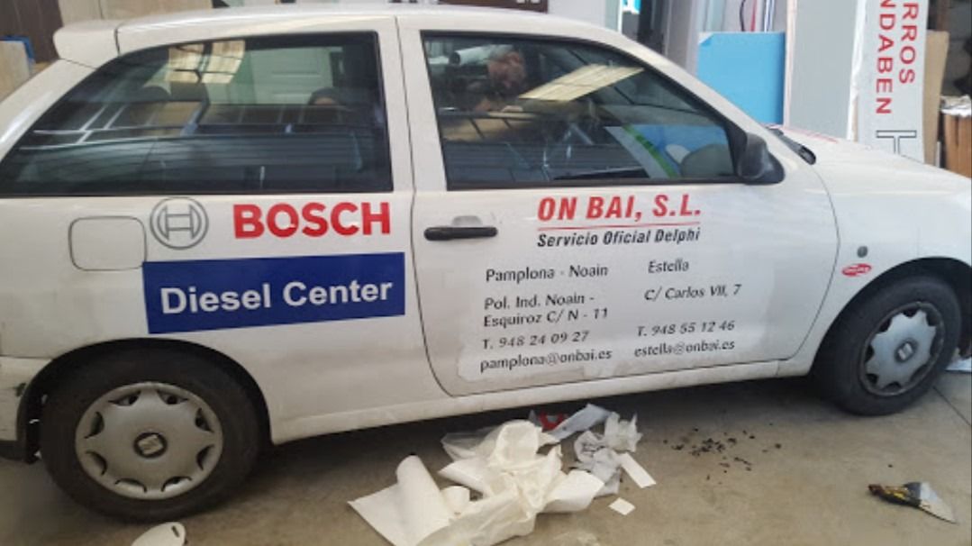 Un coche blanco Bosch Diesel Center está aparcado en un garaje.