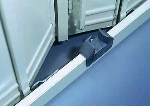 Porte d'armoire métallique avec butée de porte en caoutchouc noir sur un sol bleu.