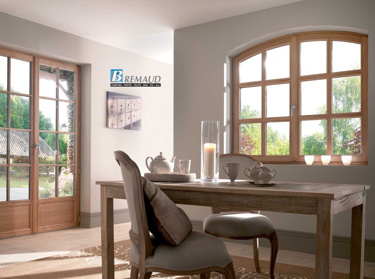 Intérieur avec fenêtres et portes en bois, table dressée avec du thé, murs clairs.