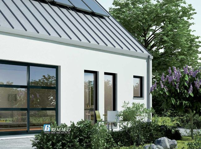 Maison blanche au toit gris, avec de grandes fenêtres et un jardin aux fleurs violettes.