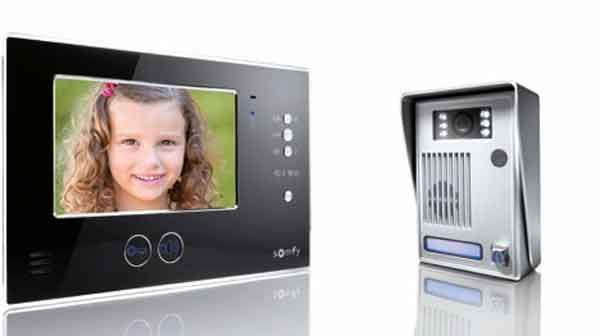 Système d'interphone vidéo : Moniteur intérieur affichant le visage de la jeune fille, à côté du boîtier caméra/haut-parleur extérieur.