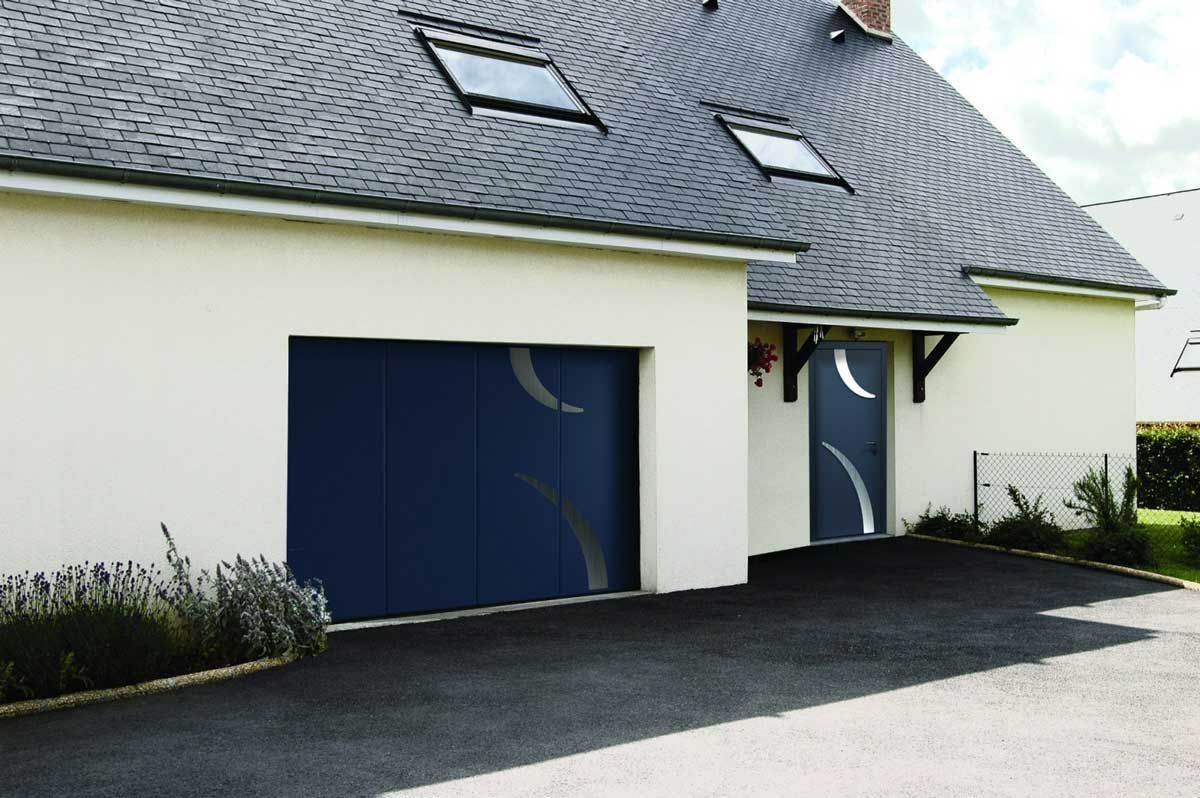 Porte de garage bleue et porte d'entrée assortie sur une maison blanche au toit gris foncé.