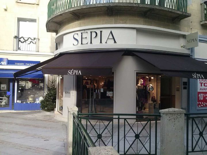 Magasin de vêtements Sepia avec un auvent et une enseigne noirs, dans un décor urbain européen.