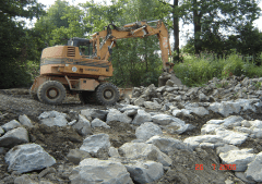 Bau einer Fischtreppe mit einem orangefarbenen Bagger