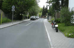 sanierte Straße mit Gehsteig aus Pflastersteinen mit geparktem Motorrad und Autos am Straßenrand