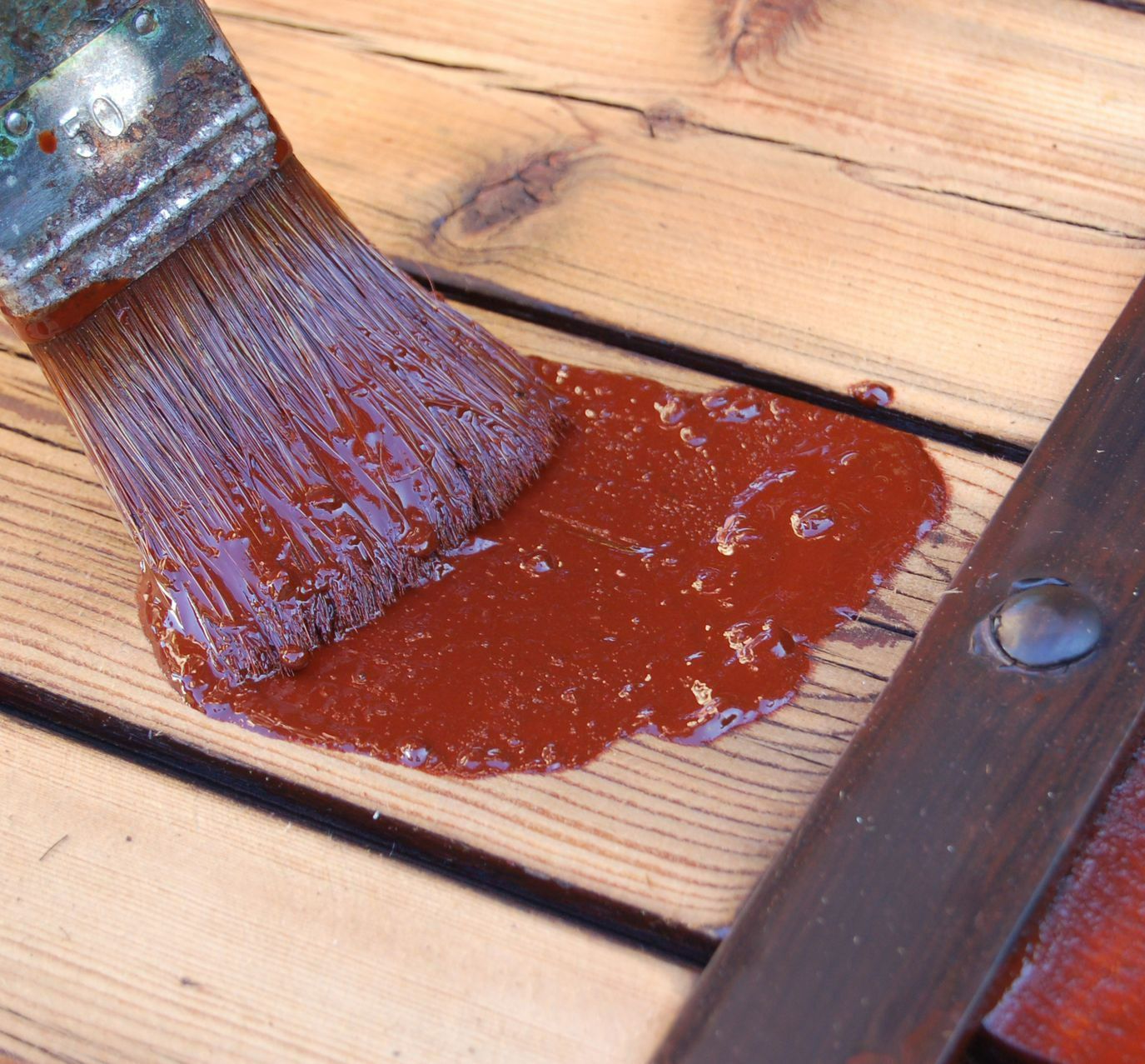 Un pinceau avec de la peinture rouge sur un support en bois.