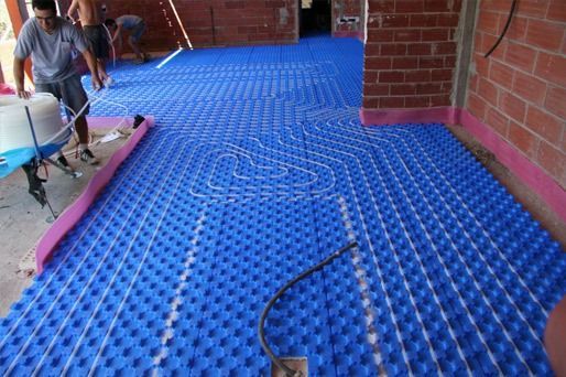 Un hombre está colocando una alfombra azul sobre un piso de ladrillo.