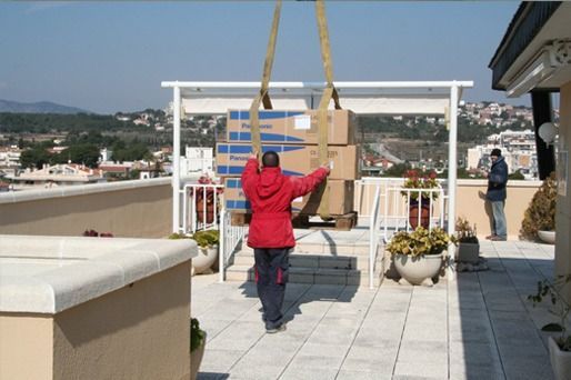 Un hombre con una chaqueta roja lleva cajas en un tejado.