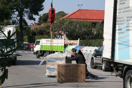 Un hombre está arrodillado frente a un camión con cajas encima.