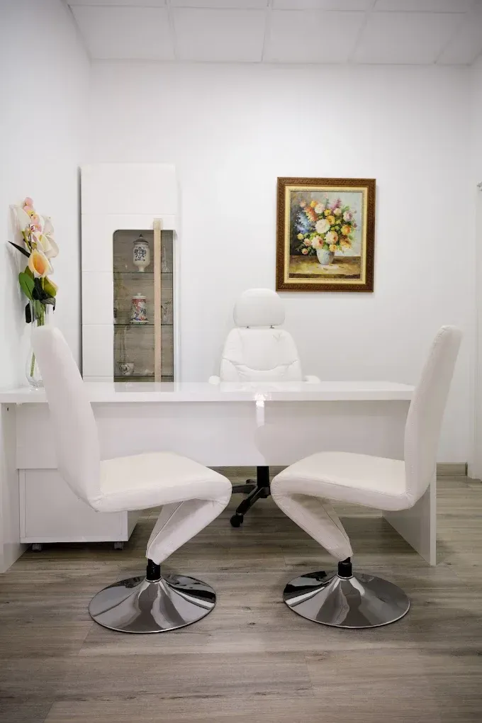 Sala de reuniones blanca y luminosa con mesa, cuatro sillas y un cuadro de flores enmarcado en la pared.