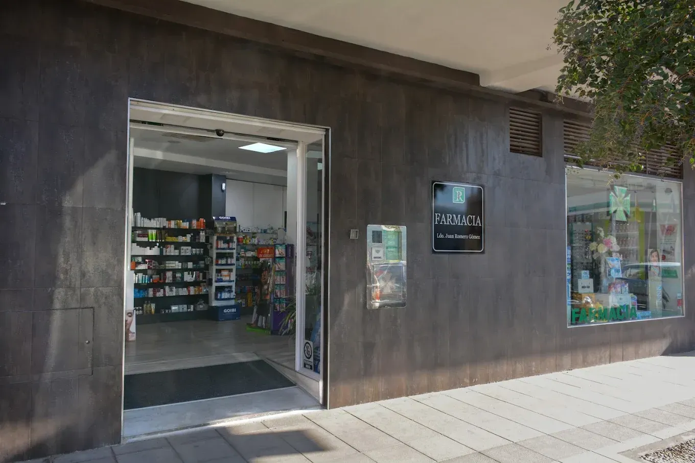 Vista de la calle de una tienda con entrada abierta, fachada oscura y escaparate.