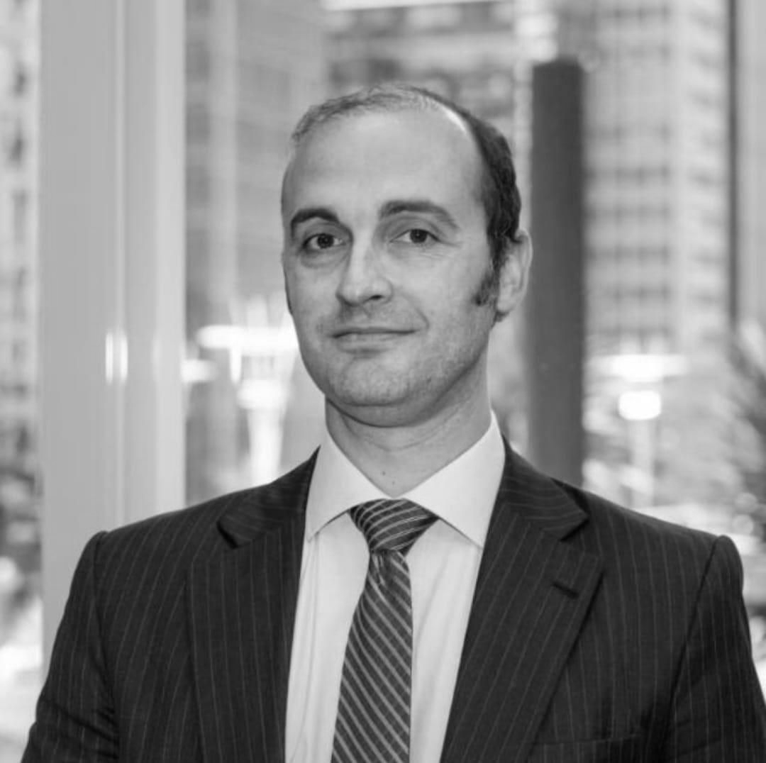 Un hombre con barba lleva traje y corbata.