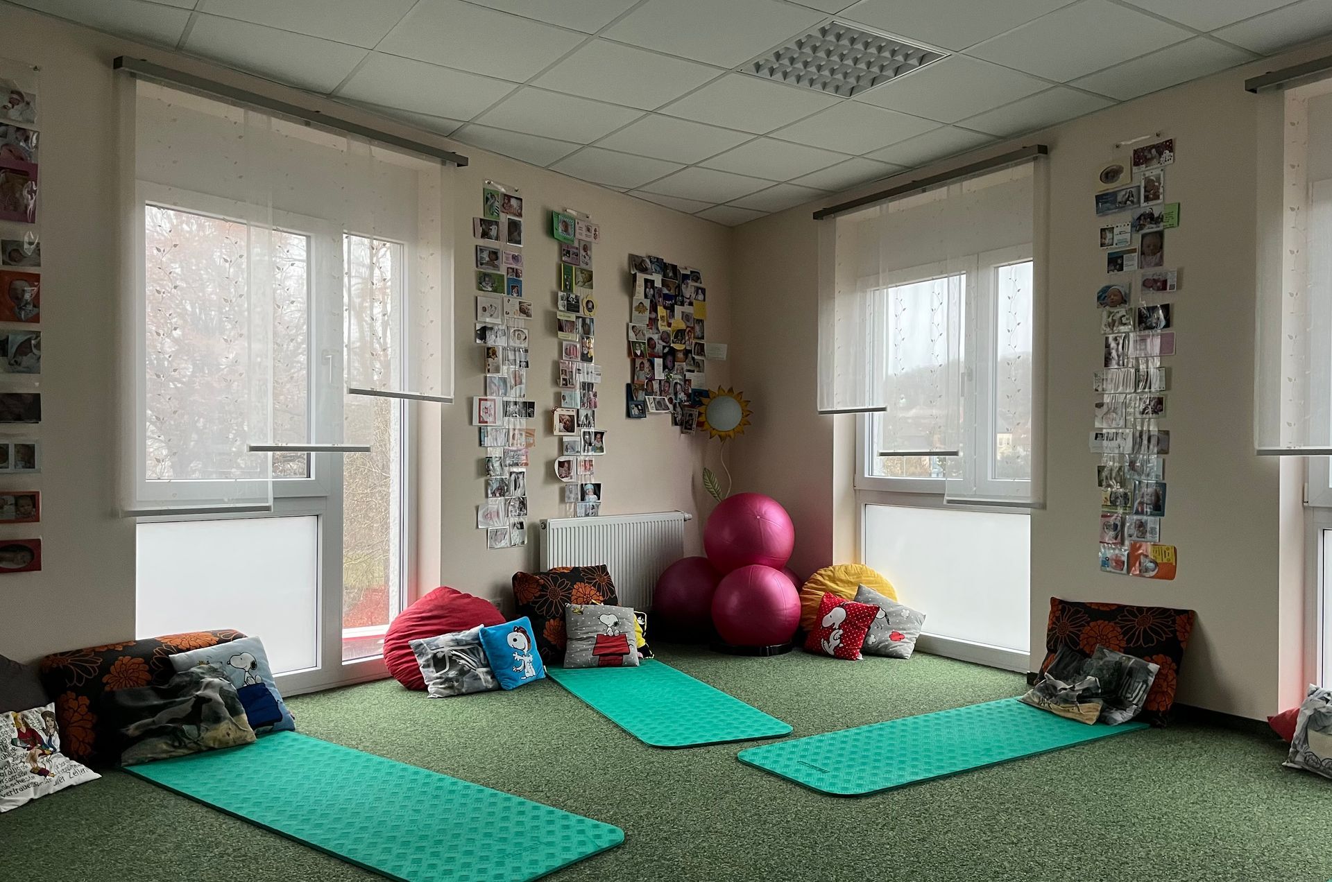 Ein Raum mit Sitzsäcken, Yogamatten und Gymnastikbällen an den Fenstern, geschmückt mit Fotos.