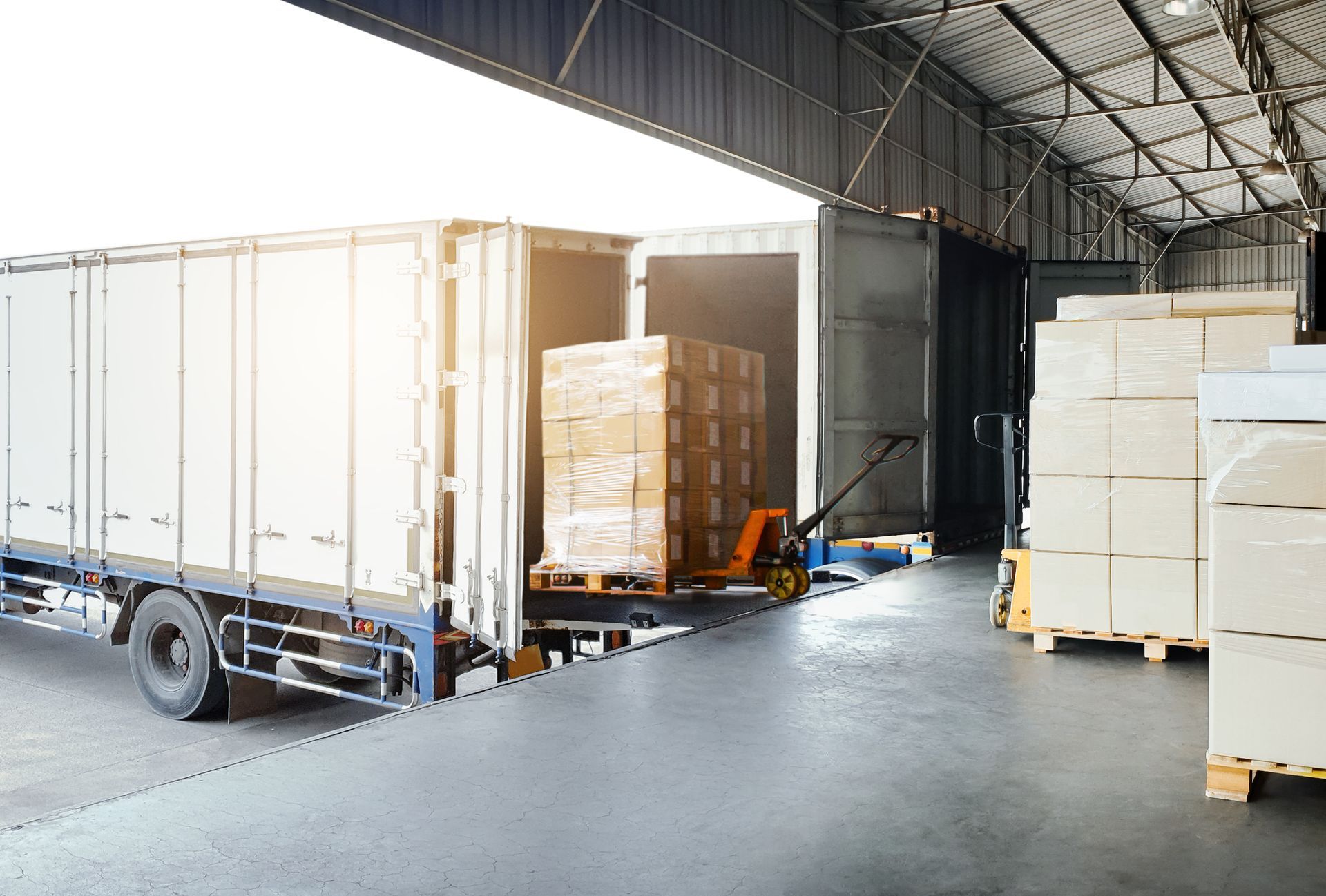 Déchargement d'un camion sur le quai de chargement d'un entrepôt ; cartons sur palettes.