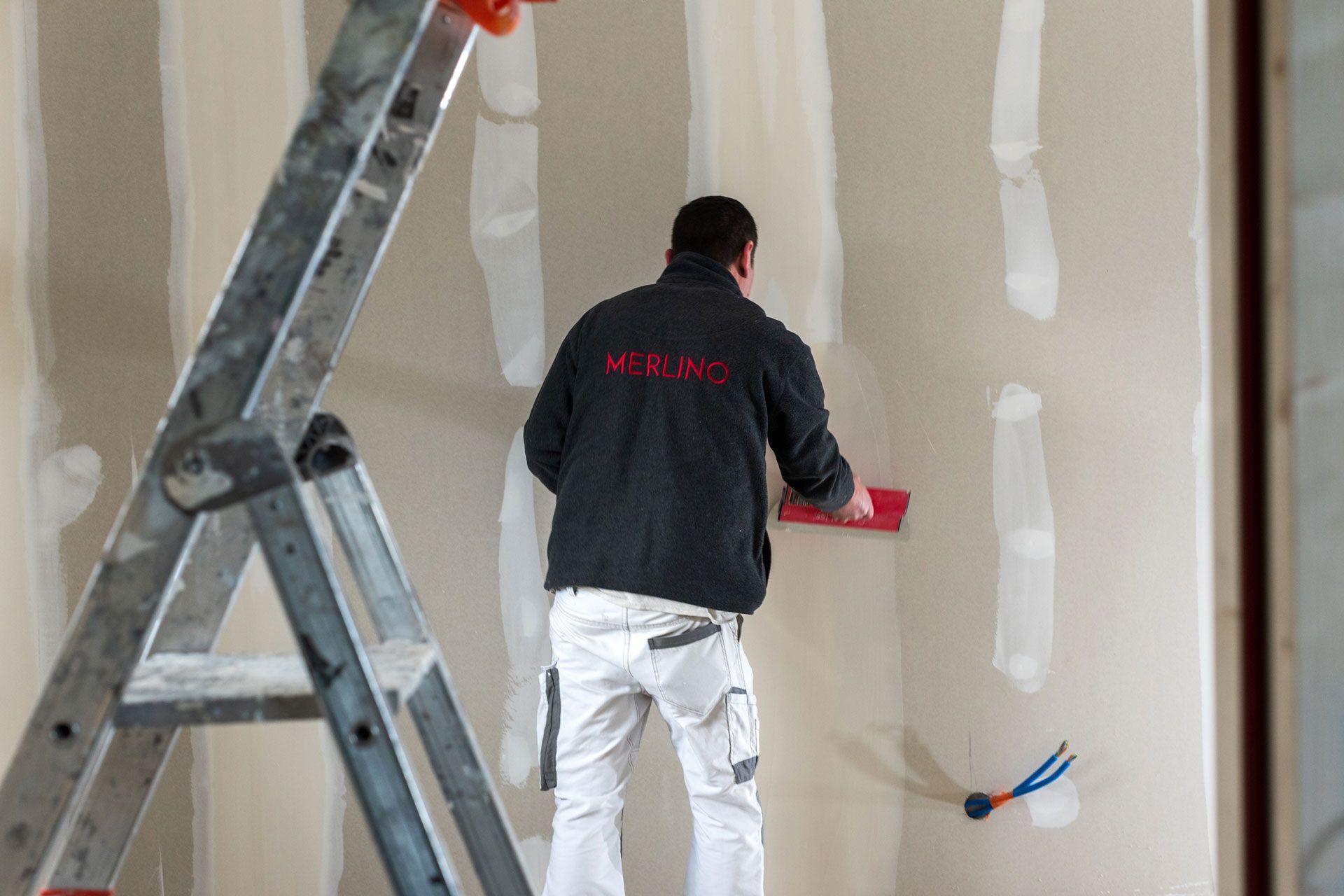 Un ouvrier de chez MERLINO Peinture finissant l'enduit sur mur