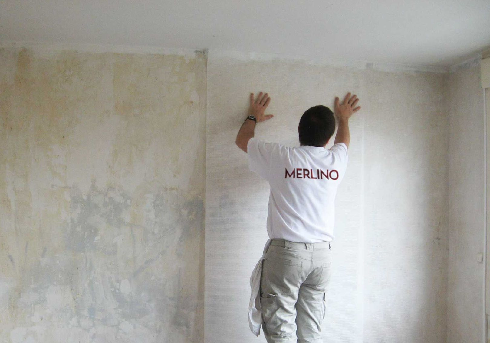 Un ouvrier posant de la toile de verre sur un mur préparé