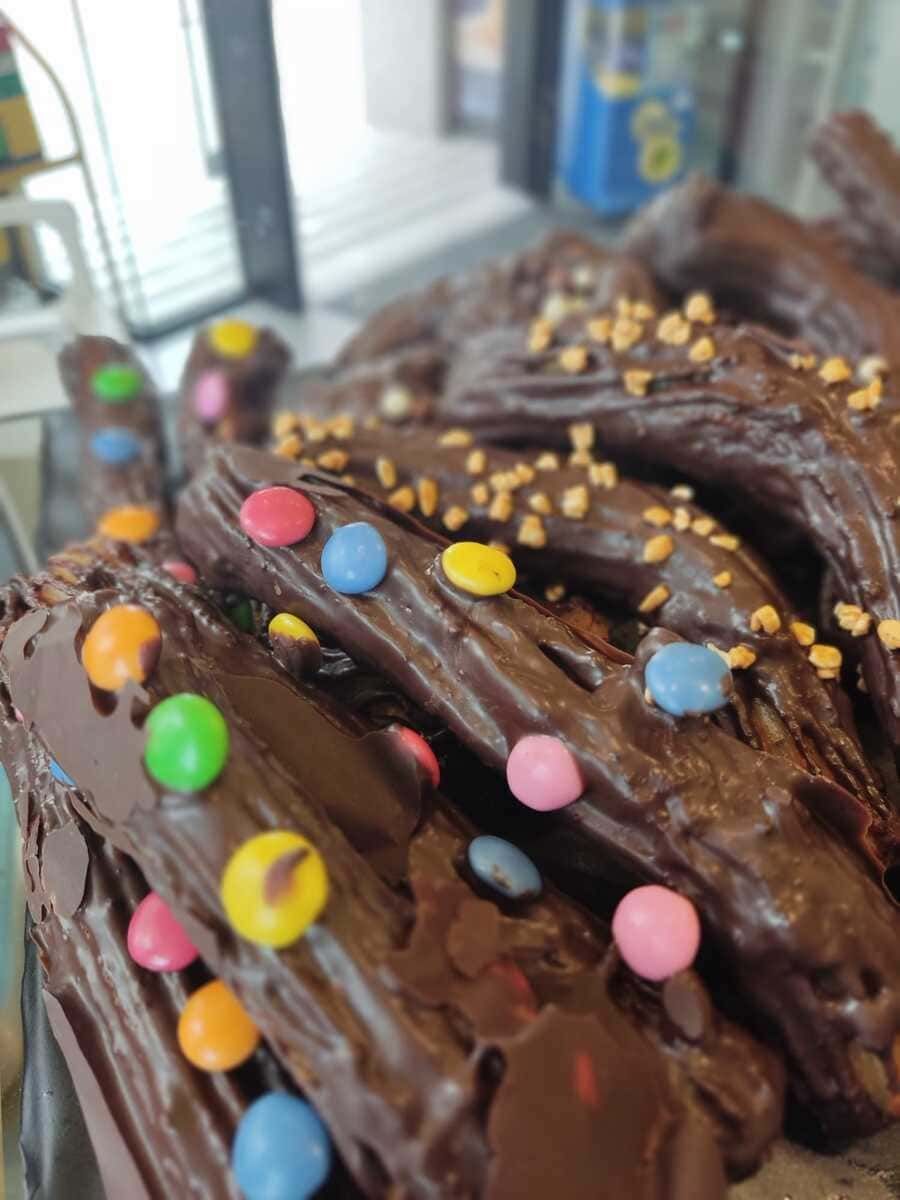 Un primer plano de un donut de chocolate con chispas de colores encima.