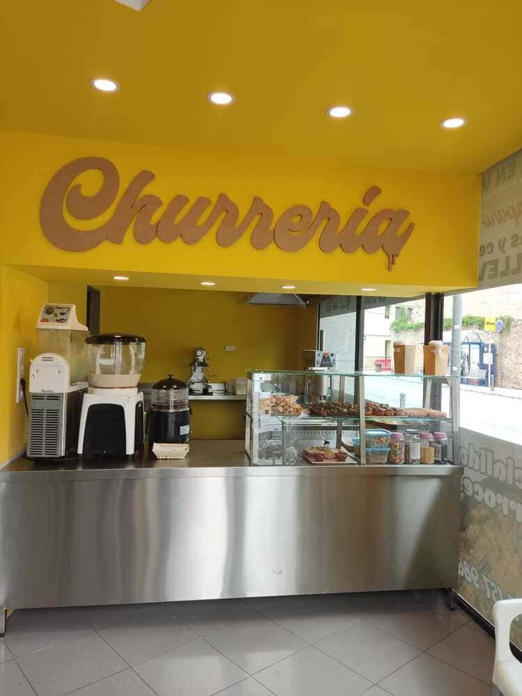 Un mostrador de acero inoxidable frente a una pared amarilla que dice churería