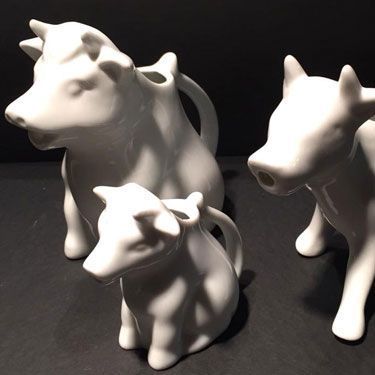Tres vacas blancas están sentadas una al lado de la otra en una mesa.