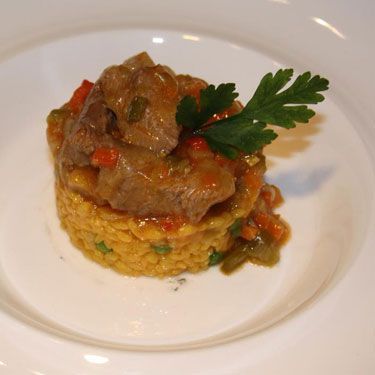 Un plato blanco cubierto con arroz, carne y verduras.