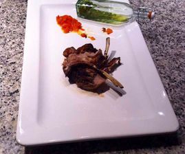 Un plato blanco cubierto con carne y salsa junto a una botella de vino.