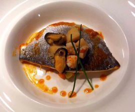 Un plato blanco cubierto con un trozo de pescado y verduras.