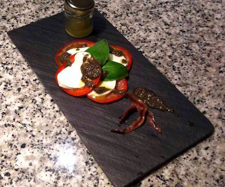 Un plato de comida con tomates y mozzarella en una mesa.