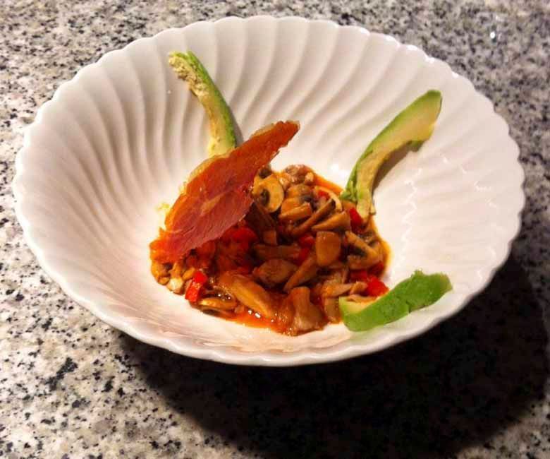 Un plato de comida con aguacate y carne en una mesa.