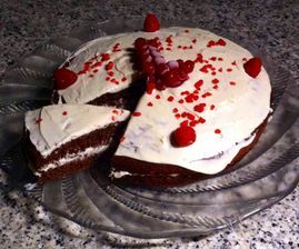 Un pastel del que se ha sacado un trozo está sobre un plato de cristal.