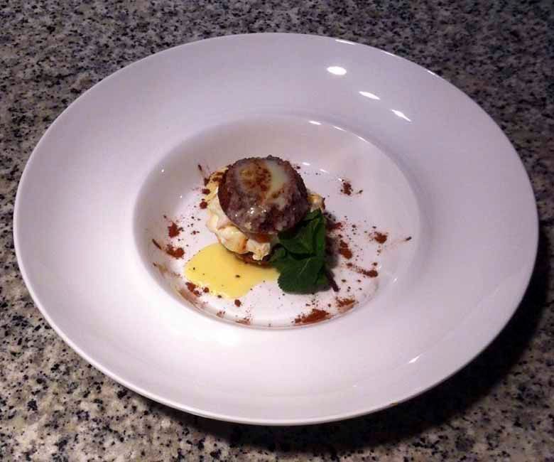 Un plato blanco con un pequeño trozo de comida encima.