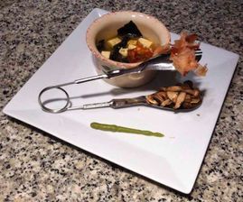 Un plato blanco cubierto con un tazón de comida y una cuchara.