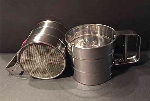 Dos tamices de acero inoxidable están colocados uno al lado del otro sobre una mesa.