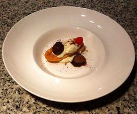 Un plato blanco cubierto con un postre sobre una encimera de granito.