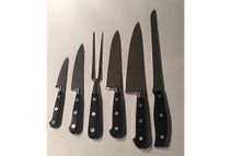 Un grupo de cuchillos y tenedores están alineados sobre una superficie blanca.